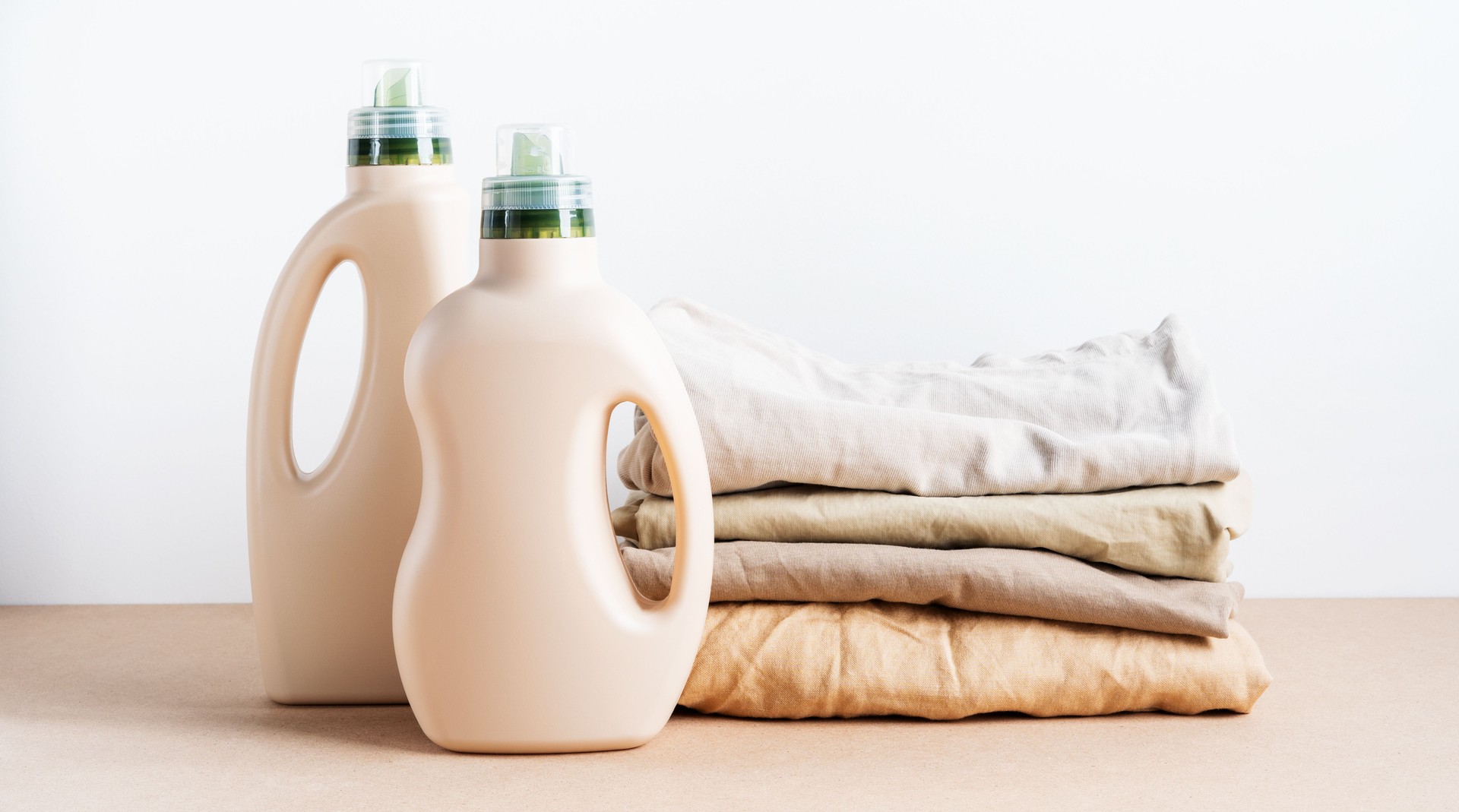 Stack of folded clean clothes with Eco Design blank bottles packaging of detergent.