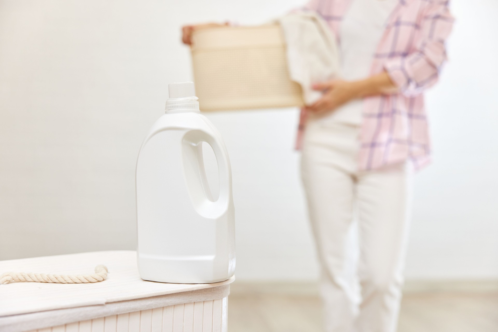 washing gel or fabric softener on white laundry basket.